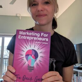 Kerri Schlottman smiling and holding Marketing For Entrepreneurs. The Quick Guide To Spark & Ignite Your Marketing Book by Beverly Cornell