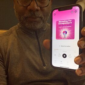 Todd Threats holding a phone with Marketing for Entrepreneurs: The Quick Guide to Spark & Ignite Your Marketing on his audible app open.